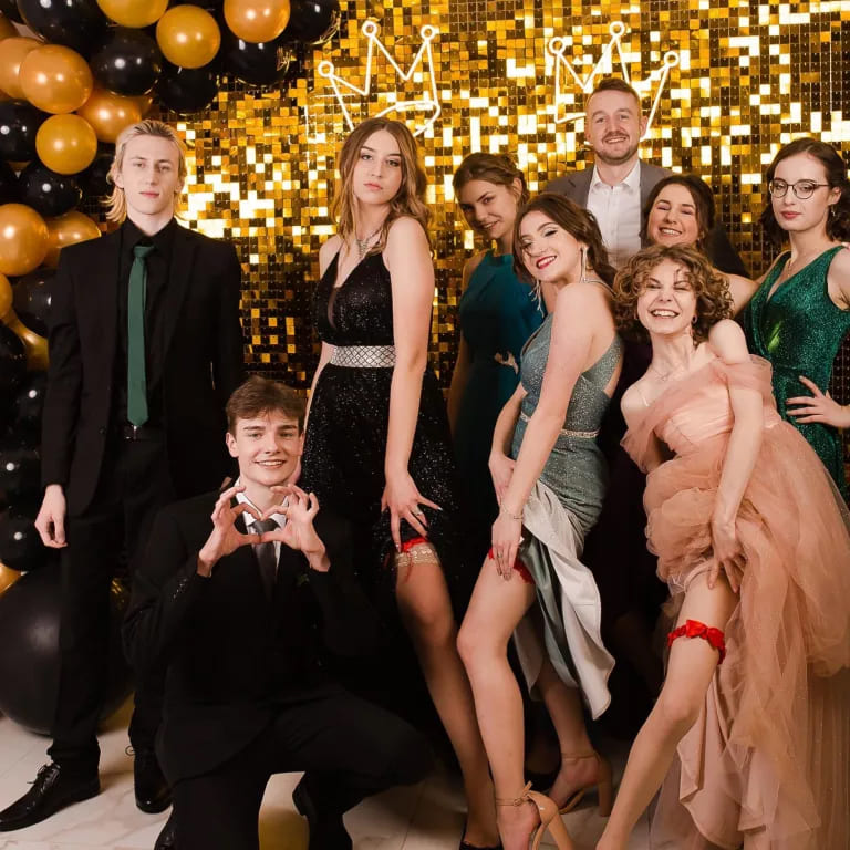 Grupowe zdjęcie na tle złotej scenografii, event formalny
